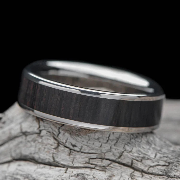 Titanium ring with Central African Blackwood inlay, 6mm mens wedding band, unique custom design, free engraving, displayed on a white sea branch.