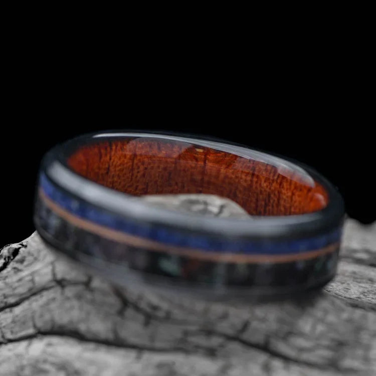 Black titanium wedding band with black pearl, lapis lazuli, and guitar string inlays on a white sea branch, 7mm unique mens ring with free engraving.