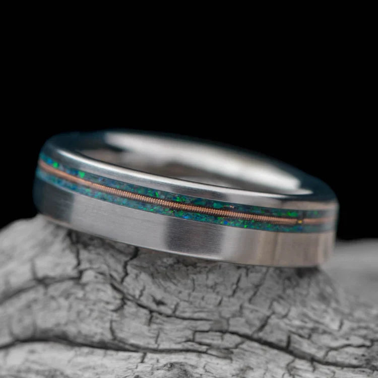 Titanium wedding band with emerald opal and guitar string inlay, custom flat profile, 5mm unique ring, on white sea branch, free engraving available.