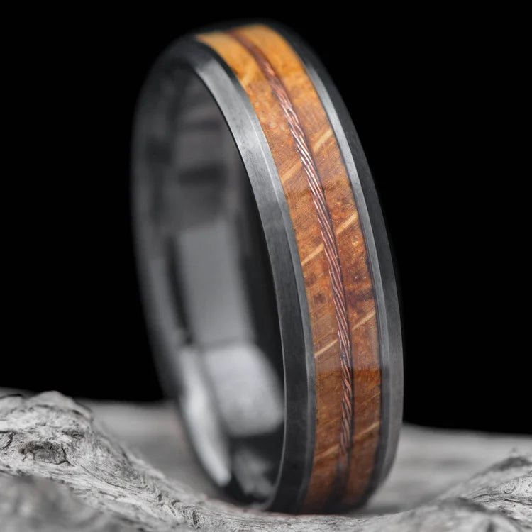 Black titanium ring with whiskey barrel oak and stranded copper wire inlays, 6mm mens wedding band, unique design, free engraving, displayed on a white sea branch.