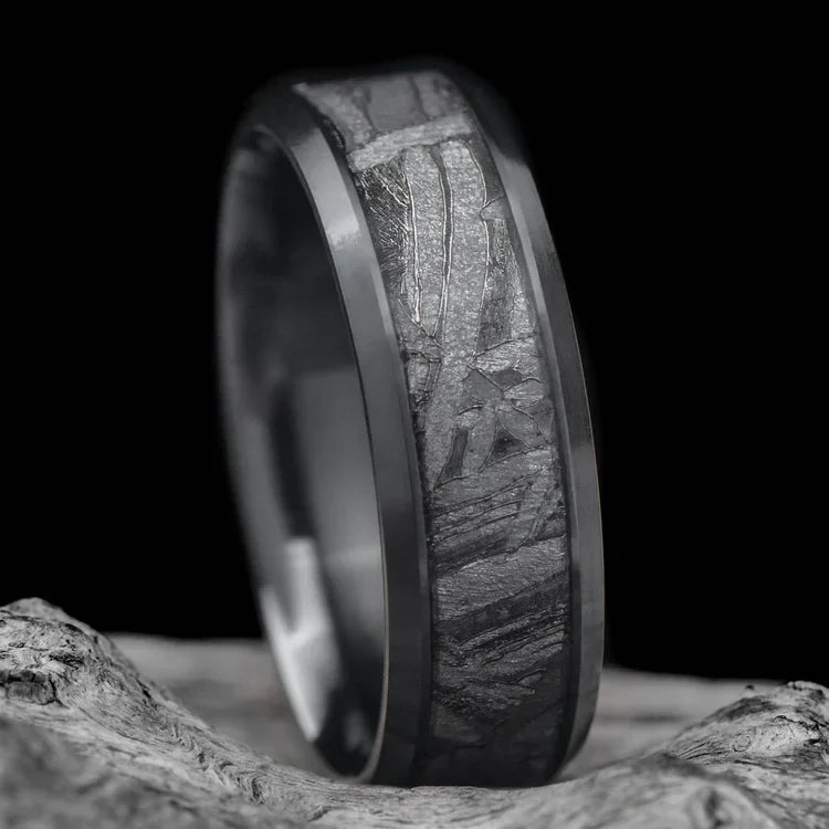 Black titanium mens wedding ring with central meteorite inlay, 7mm wide, displayed on a white sea branch, offers free engraving and unique design.