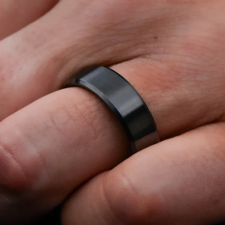 Mens black titanium wedding band with T-Rex inner sleeve, 8mm brushed bevel profile, shown on a hand, unique mens ring with free engraving.