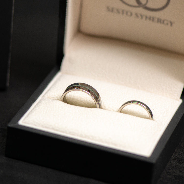Two gold rings in an open black box with 'Sesto Synergy' branding.