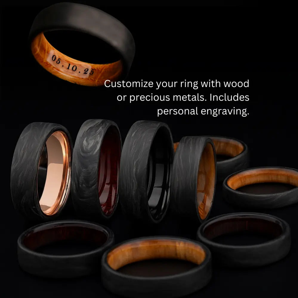 A collection of custom black wedding rings from "The Quest" line, featuring inner inlays of wood and precious metals, with an engraved date on one ring.