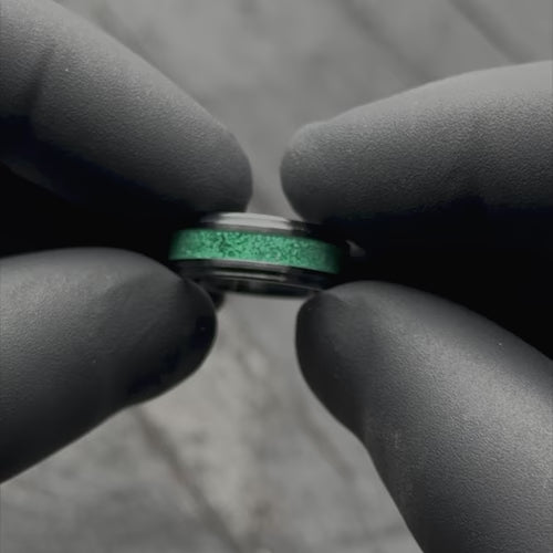 Black titanium wedding band with central malachite inlay, 7mm mens ring, unique design, free engraving, showcased with black gloves.